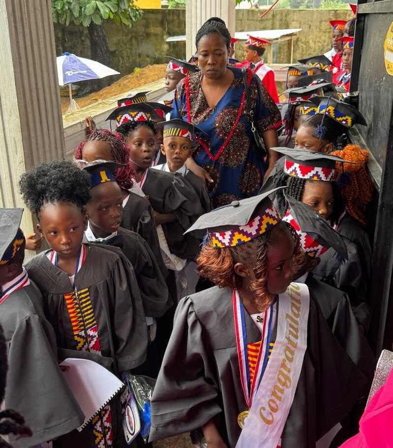 A group of pupils in graguation robes with a teacher