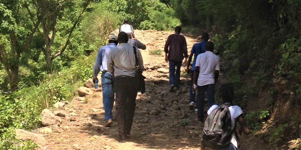 group of individuals walking down a dirt road in a rural area