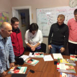 group of people standing around a table with documents